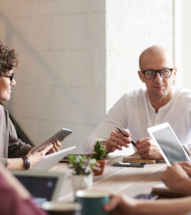 Group of professionals engaged in a brainstorming session around a table in a contemporary office space.